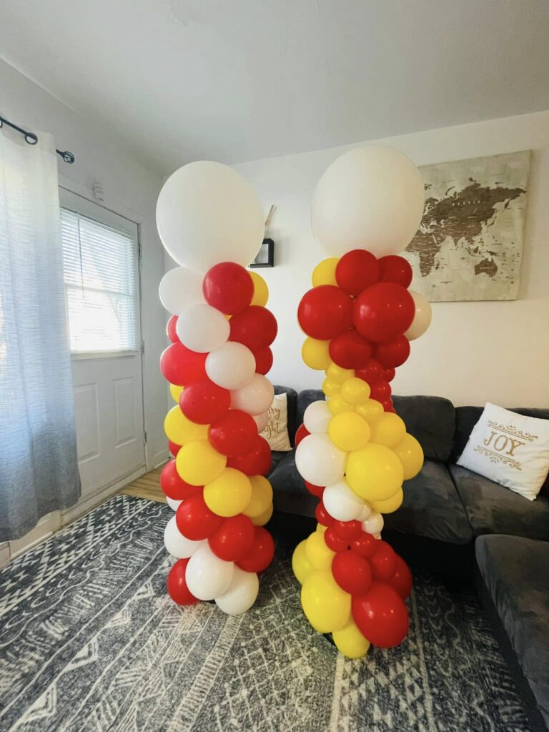 Vibrant red, white, and yellow balloon towers for a home birthday party in Montreal, featuring organic clusters for a festive living room celebration.