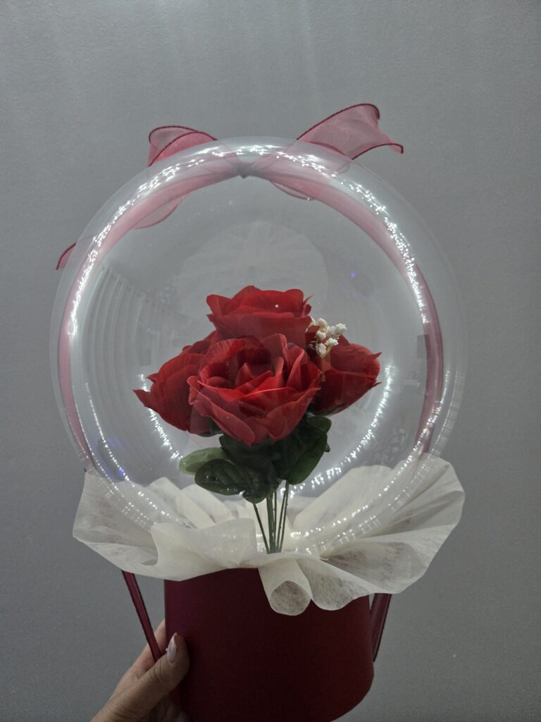 Bespoke Bobo flower box featuring vibrant red roses encased in a crystal-clear dome with a personalized red base, handcrafted in Montreal by La Balloonerie.
